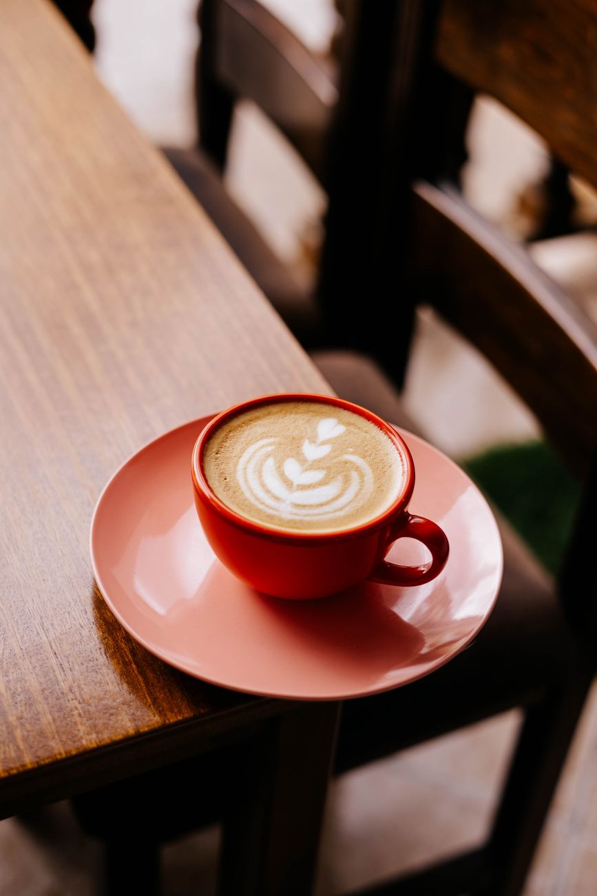 latte art in red cup on cafe table